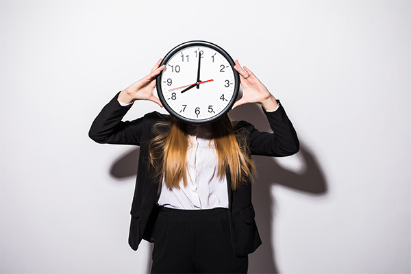 Jeune femme portant une horloge se demandant comment mieux gérer son temps de travail.